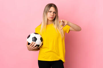 Young football player woman isolated on pink background showing thumb down sign