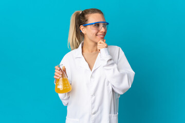 Young scientific woman isolated on blue background looking to the side and smiling