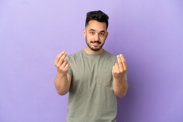 Fototapeta premium Young caucasian man isolated on purple background making money gesture