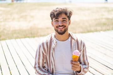 Handsome Arab man with a cornet ice cream at outdoors smiling a lot