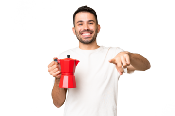 Young caucasian man holding coffee pot over isolated chroma key background points finger at you with a confident expression