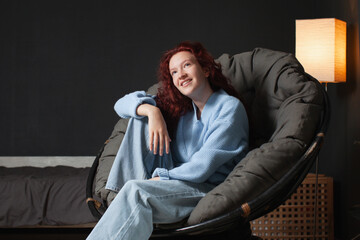Portrait of cheerful young woman sitting on sofa at home