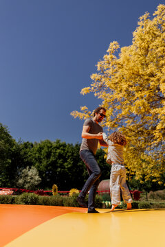 Man and child playing on colorful outdoor bouncer