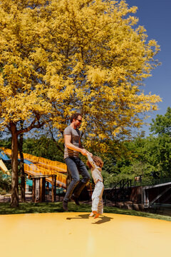 Man and child playing on colorful outdoor bouncer