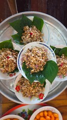 Colorful Traditional Dish Served on Plates with Fresh Leaves and Toppings on Round Tray