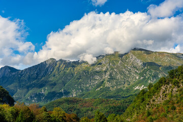 Fototapeta premium Green meadows next to the high mountains of the Julian Alps in the town of Kobarid, Slovenia.