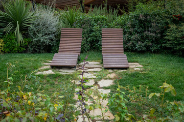 Obraz premium Wooden Lounge Chairs in Lush Garden Setting