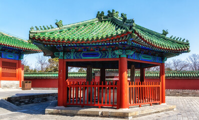 Fototapeta premium Traditional Chinese architecture at the Temple of Heaven, featuring vibrant red walls and distinct green-tiled roofs