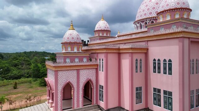 Aerial view of the pink AnNur Mosque in Bintan showcasing its elegant domes and reflection surrounded by lush greenery and tranquil water scenery