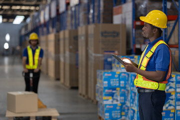 Warehouse man worker wearing safety uniform use digital tablet while giving directions to colleague. Concept of logistics, warehouse management, inventory control and teamwork.