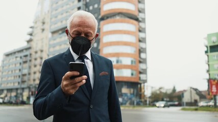 Successful senior businessman wearing a protective face mask walking on a city street and answering a phone call during the coronavirus pandemic, with urban traffic in the background - Powered by Adobe