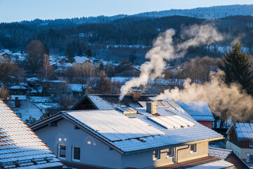 Snow-dusted rooftops, solar panels and chimneys sending smoke into cold air above a small German...