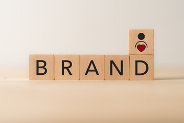 Building brand with customer loyalty concept. Wooden blocks spelling “BRAND,” and a heart and person icon. Brand building, trust and customer loyalty.