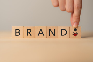 Building brand with customer loyalty concept. Wooden blocks spelling “BRAND,” and a heart and person icon. Brand building, trust and customer loyalty.