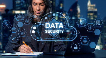 Woman working on laptop with data security holograms in futuristic digital interface on city night...