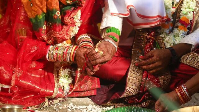 Hands of the bride and groom in wedding Ceremony. Hindu wedding ritual. Odia Wedding. Hindu Wedding Ceremony with Burning Fire and Offering Ritual with People and Golden Details.