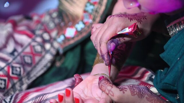 Skilled artist applies intricate traditional mehndi on a bride hand during an indian wedding ceremony.