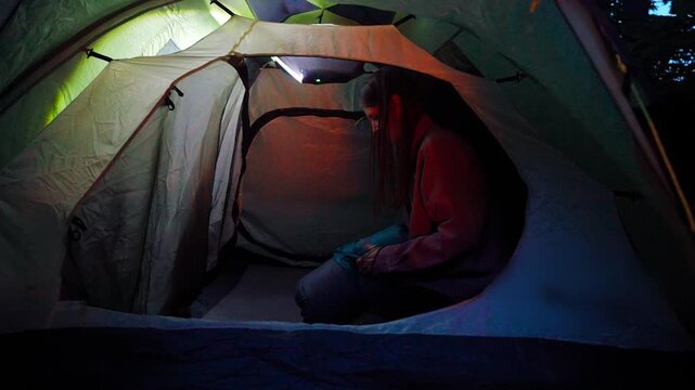 Girl hiking alone in a summer forest. Going to bed in a tent