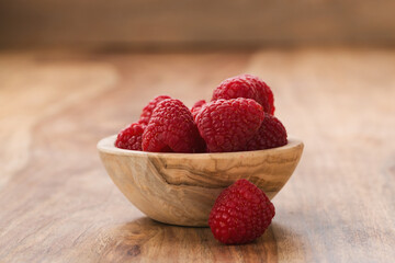 fresh raspberries in wood bowl on table