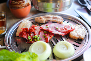 Korea BBQ style restaurant. Asian traditional pickle vegetable ingredients on table with people grilling background.
