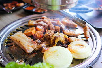Korea BBQ style restaurant. Asian traditional pickle vegetable ingredients on table with people grilling background.
