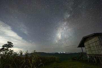 Tranquil night landscape featuring rustic cabin under beautiful star filled sky. magnificent Milky...
