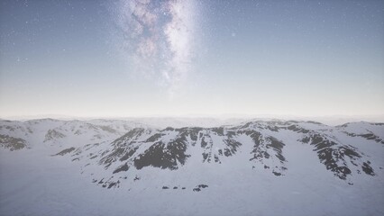 Snow covered mountains rise majestically beneath a twinkling starry sky as dawn breaks. The serene landscape evokes tranquility, inviting exploration and adventure in natures beauty.