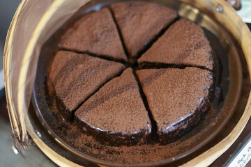 Homemade chocolate cake sliced into six rich wedges for sharing. This dark, decadent dessert, dusted with cocoa powder top, offers an indulgent and appetizing sweet treat for party or celebration