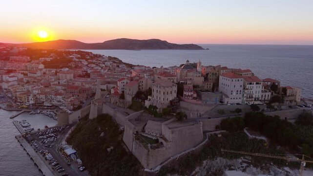 Aerial view of morning coastal fortress Calvi, golden sunrise citadel and surrounding landscape. Corsica. France