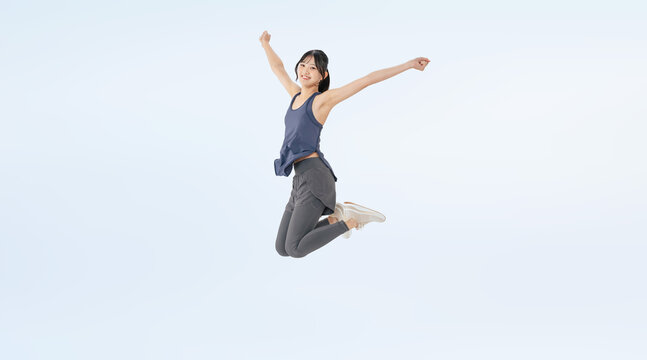 ジャンプするスポーツウェアの女性の全身写真(切り抜き背景透過PNGも販売しております。↓作成者リンクから「PNG」で検索してください)