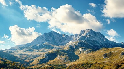 A majestic mountain range with snow-capped peaks and lush green valleys under a clear blue sky with fluffy white clouds.