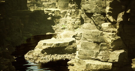 A tranquil landscape showcases dramatic rock formations beside calm water. The unique geological features create a peaceful atmosphere in a secluded natural setting.