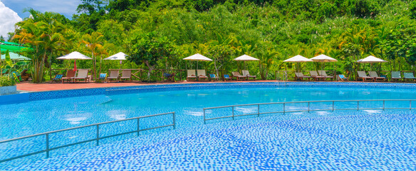 swimming pool at a tropical luxury resort by the sea in summer. Tourism and recreation. Landscape panorama with a pool and sun loungers and umbrellas