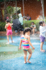 Beautiful adorable child kindergarten girl enjoying play in outdoor water park