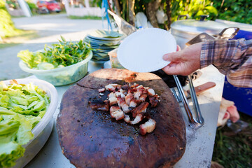 A man grills pork in a crispy, fragrant pot at a party. The crispy pork chops are a popular dish in Thailand.