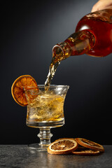 Rum or whiskey is poured from a bottle into a glass with ice.
