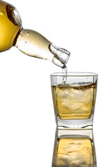Pouring Whiskey from a bottle into a glass with ice on a white background.