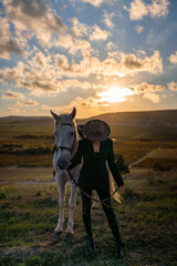 Woman horse sunset fashionable rider standing with majestic white animal at golden hour