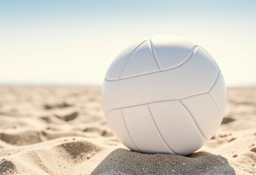 White volleyball resting on sandy beach under a clear blue sky