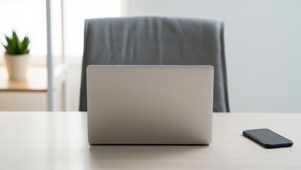 Fototapeta premium Minimalist workspace featuring a laptop, smartphone, and plant on a desk