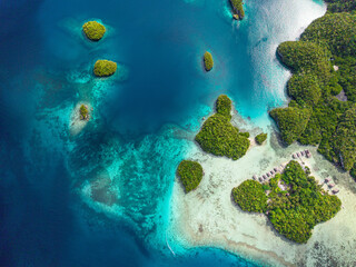 Aerial view of calm blue lagoon surrounded by lush green tropical islands in Raja Ampat, Indonesia.  
