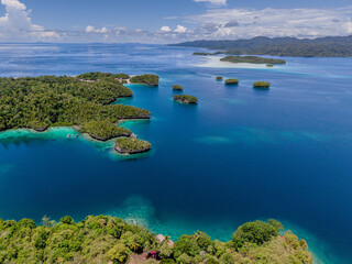 Aerial view of calm blue lagoon surrounded by lush green tropical islands in Raja Ampat, Indonesia.  
