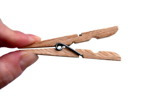 A wooden clothespin in hand isolated. An open clothes peg held in fingers.