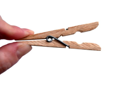 A wooden clothespin in hand isolated. An open clothes peg held in fingers.