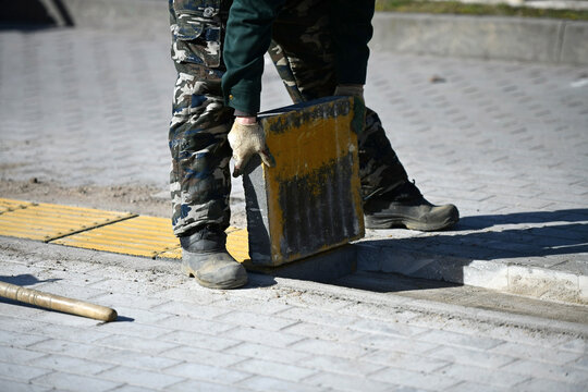 A worker lays a concrete block on a city street.