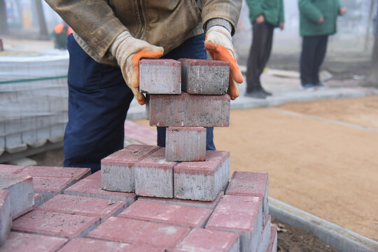 A man lays a curbstone to create a path for pedestrians.