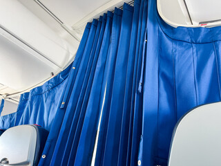 Interior view of blue curtains in a modern vehicle, showcasing the fabric texture and design, with a glimpse of seating area and ambient lighting enhancing the atmosphere