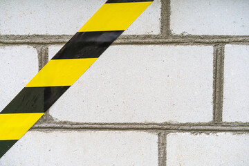 Yellow and black ribbon on a white brick foundation.The danger of construction.Major renovation of...