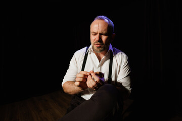 Upset actor in shirt and suspenders performing on theater stage 