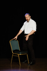 Actor performing near chair on theater stage 